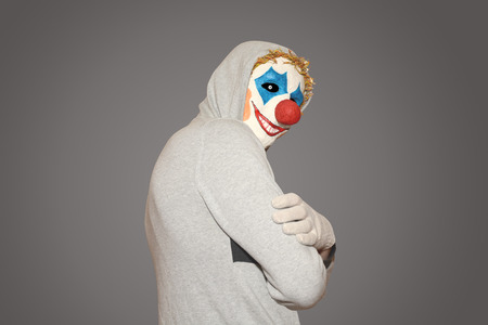 masked man evil clown stands sideways on a gray backgroundの写真素材