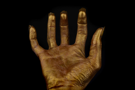terrible human hand on a black background, The golden color of human skin