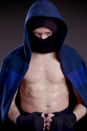Man practicing martial arts hid his face behind a mask. Boxer on a dark backgroundの写真素材