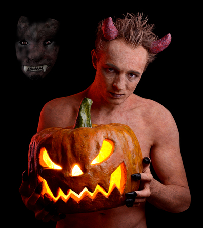 Man in the guise of the devil and with a pumpkin in his hands. On the holiday of Halloween
