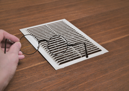 Inspection of dusty ventilation grille. Magnifying Dust Detail with Magnifying Glass
