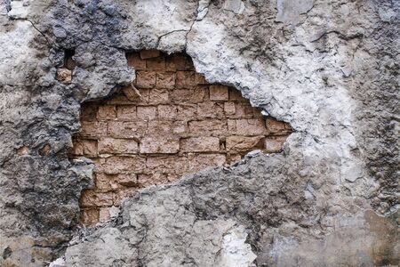 Destroyed wall abstract background.  brick wall cracked and a very old stucco fell off. Damage to the facade of the buildingの写真素材