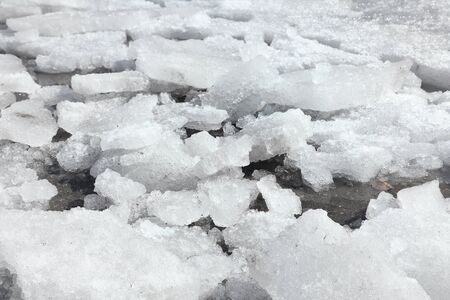 Broken dirty ice on an asphalt road. In the spring, utilities work. Thaw. Frozen footpath.