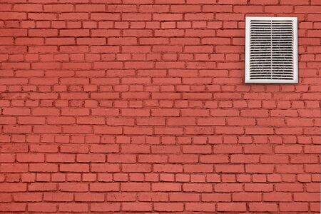 Dirty, dusty ventilation grill on a red brick wall. Concept of pollution of ventilation systems.