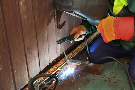 Welding work on the street. Welder cooks metall parts on the ground. Construction industry