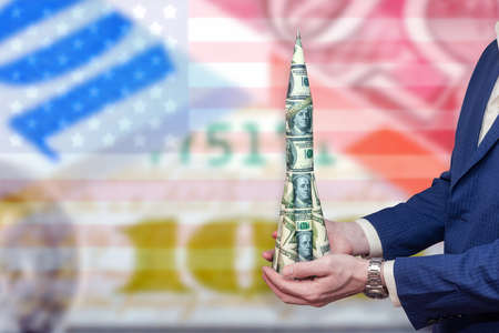 Ð¡oncept of the growth of the dollar. Money rocket in the hands of a businessman against the background of the American flag and various currencies. Successful business. Trade and investment.の写真素材
