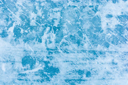 Ice blue background with skate tracks. Skating rink. Frozen water, sea. Frosty ice texture with...