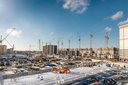 city Barnaul. Russia. March 11, 2021. Construction of residential buildings from reinforced concrete and bricks. Tower crane work, house erection. Enthusiasts st. Industrial zone. Construction machineryのeditorial素材
