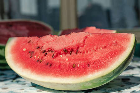 Piece of fresh cut watermelon on the table. Sweet berry on a street table in the country, soft focus.の写真素材