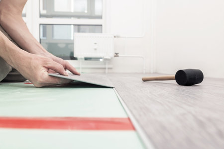 Man lays a quartz laminate on the floor. Repair of premises. Contemporary flooring. Soft focus.の写真素材