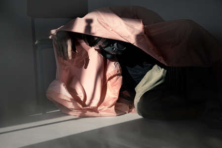 Man in a respirator is covered with a cloth during a gas attack in a dark room. The concept of...