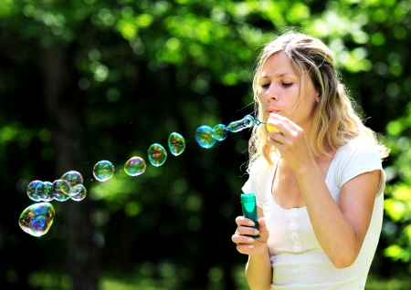 young woman blowing bubbles outdoorsの写真素材