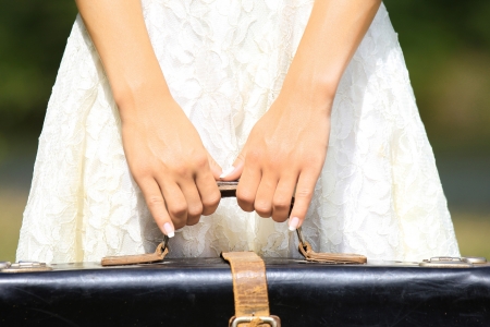 the hands of a young woman holding a suitcaseの写真素材