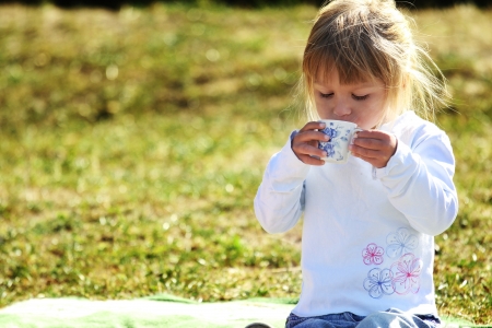 beautiful little girl on nature with teaの写真素材