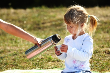 beautiful little girl on nature with teaの写真素材