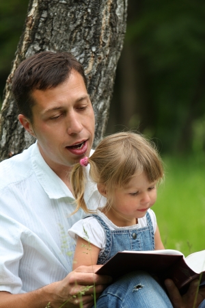 young father with baby daughter reading the Bibleの写真素材