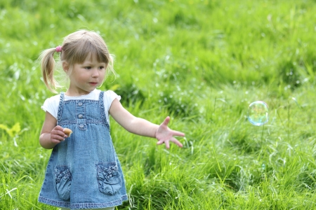 little girl with soap bubbles in natureの写真素材