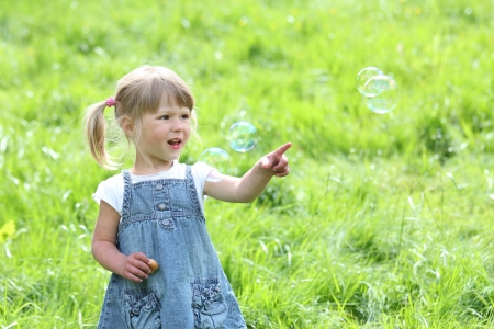 little girl with soap bubbles in natureの写真素材
