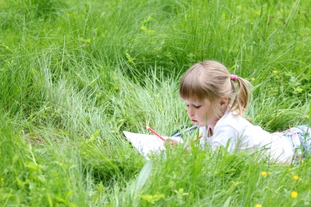beautiful little girl on the nature draws pencilsの写真素材