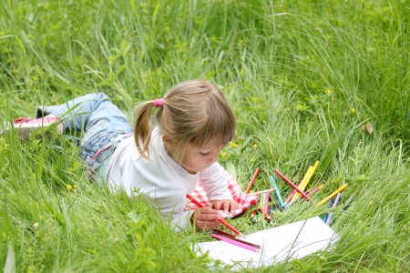 beautiful little girl on the nature draws pencilsの写真素材
