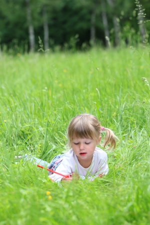 beautiful little girl on the nature draws pencilsの写真素材
