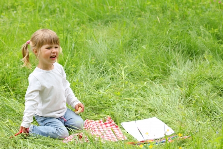 beautiful little girl on the nature draws pencilsの写真素材