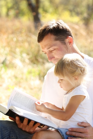young father with his little daughter reads the Bibleの写真素材