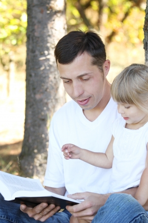 young father with his little daughter reads the Bibleの写真素材