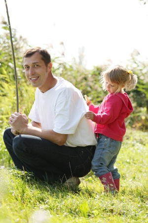Dad and little daughter near a lake in rubber bootsの写真素材