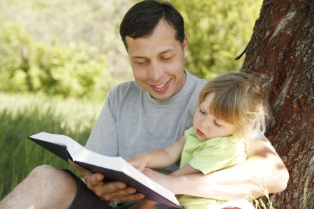 young father with his little daughter reads the Bibleの写真素材