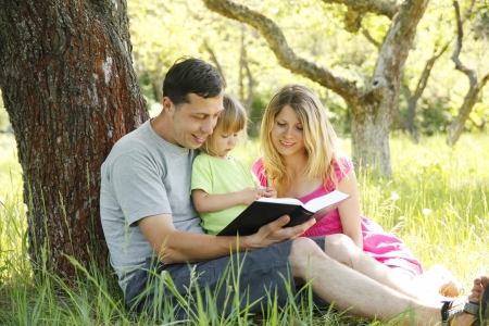Young family reading the Bible in natureの写真素材