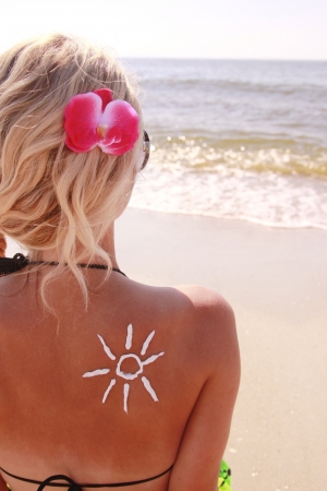 of sun cream on the female back on the beachの写真素材