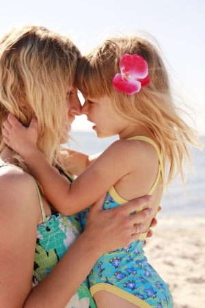 Mama and her little daughter playing on the beachの写真素材