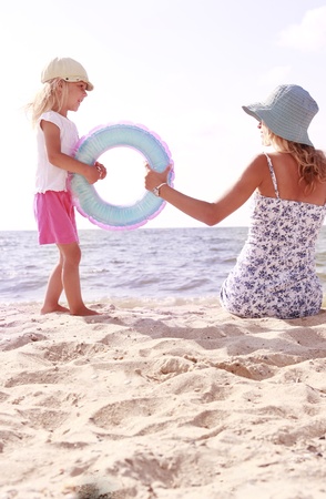 Mama and her little daughter playing on the beachの写真素材
