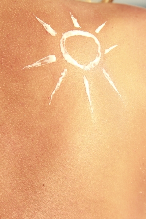 of sun cream on the female back on the beachの写真素材