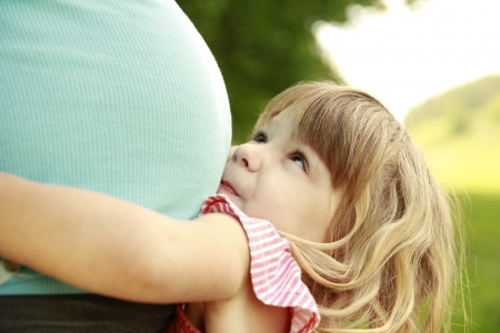a little girl near the belly of his pregnant mother on natureの写真素材