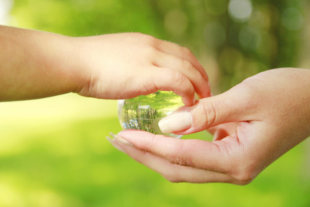 a glass globe in the hand of a parent and child の写真素材