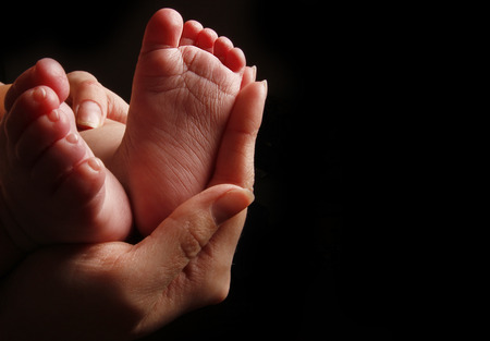 a newborn little baby feet in mother's hands の写真素材