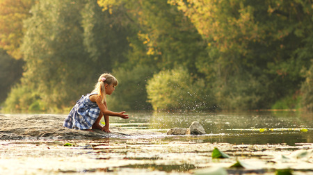 beautiful little girl in nature play near lakeの写真素材