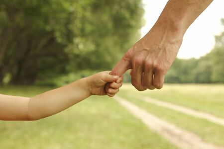the parent holds the hand of a small childの写真素材