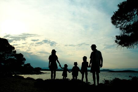 happy family silhouette at sunset by the seaの写真素材