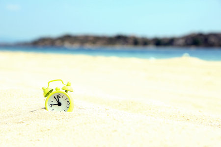 green clock on the sand on the beach in summer