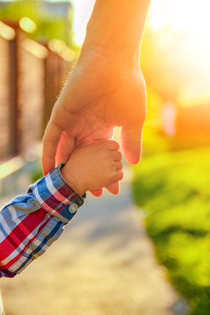 the parent holding the child's hand with a happy backgroundの写真素材
