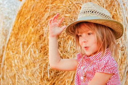 Baby girl on a haystack happy on the field. Background with children a joyful childhood.の写真素材
