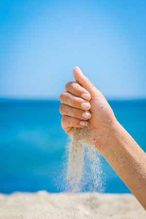 Hands pour sand off the sea on nature on a journey. Vacations at sea sand time passes.の写真素材