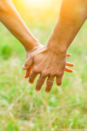 Hands of a happy couple in love outdoors in the summer parkの写真素材
