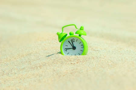beautiful alarm clock in the sand by the sea backgroundの写真素材