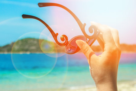 beautiful hands with sunglasses by the sea on nature backgroundの写真素材
