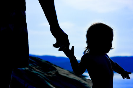 happy parent with child in nature by the sea silhouetteの写真素材