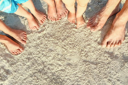 beautiful family legs on the sand by the seaの写真素材